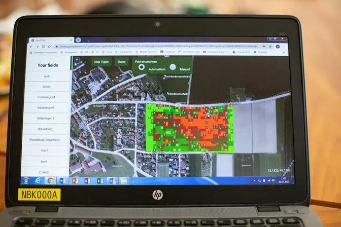 Ein aufklappter schwarzer Laptop zeigt eine Karte mit landwirtschaftlich genutzten Flächen und eine Ortschaft.